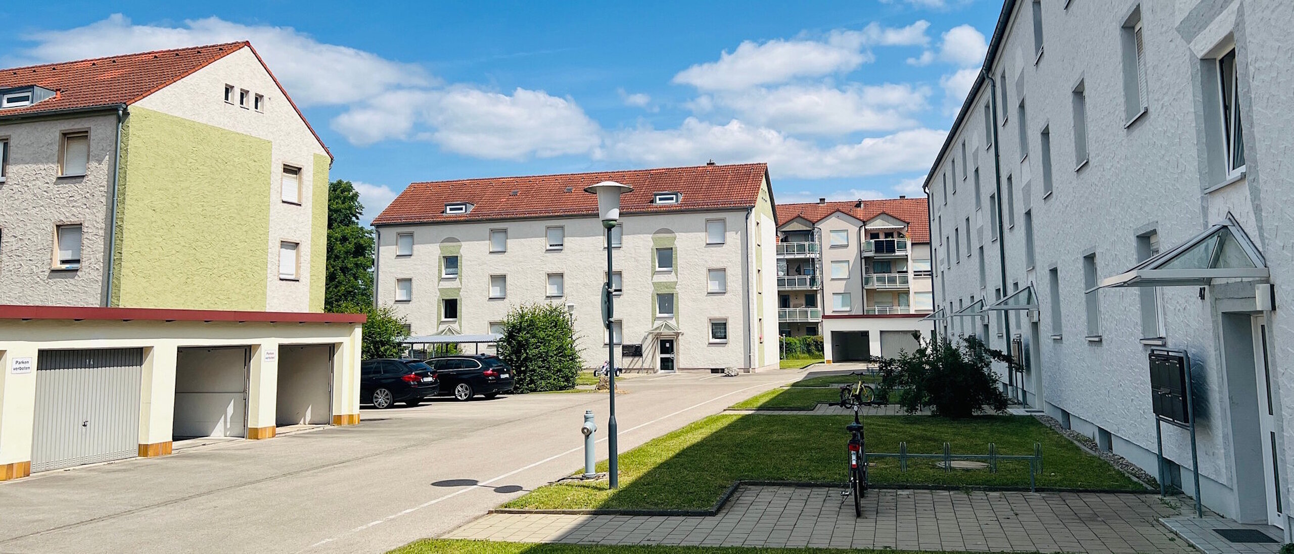 Quartier mit mehreren Mehrfamilienhäusern, dreigeschossig mit Schrägdach, dazwischen Anliegerstraßen und Grünanlagen