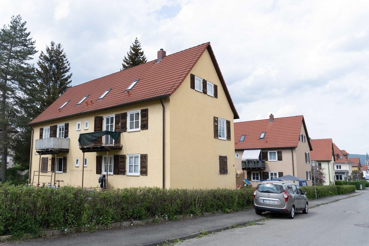 Chiron Siedlung vor der Sanierung Mehrfamilienhaus mit Schrägdach vor Sanierung, davor eine Straße