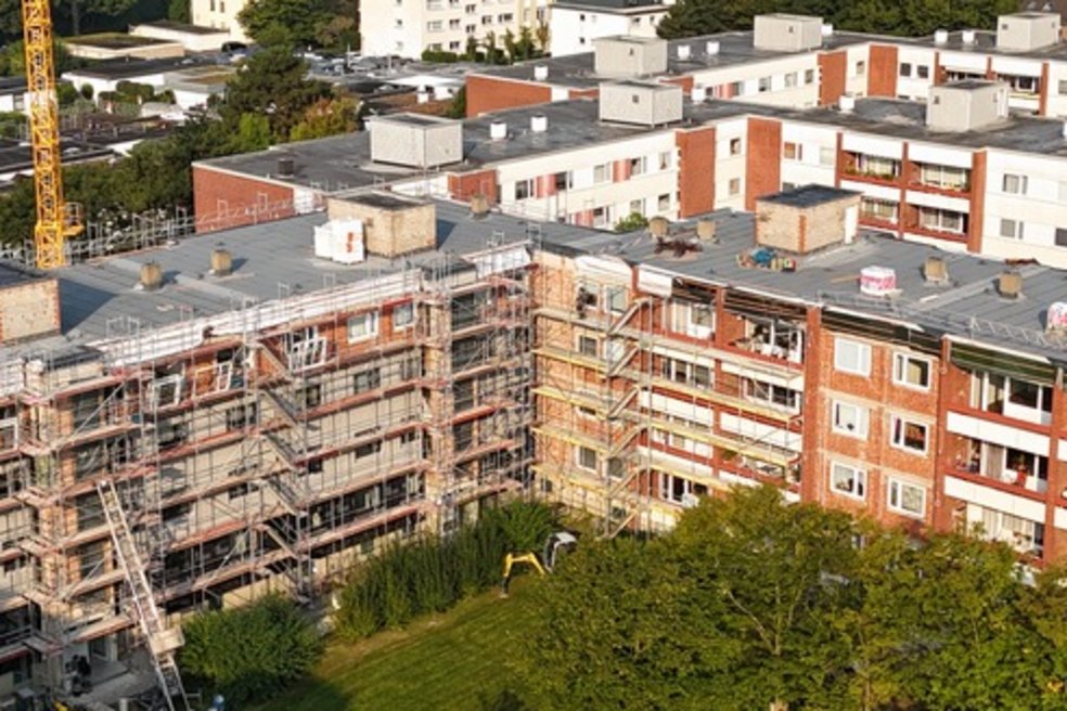 Luftaufnahme eines Wohnkomplexes mit Grünflächen und Laubbäumen