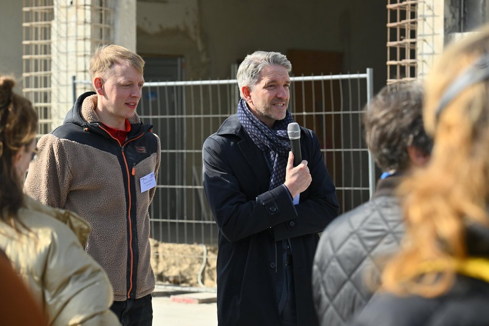 Laut Martin Sowinski, Mitglied der BIM-Geschäftsleitung, werden innovative Themen wie das serielle Sanieren im InnoLab der BIM aktiv vorangetrieben. Person mit Mikrofon in der Hand spricht zu einer Personengruppe.