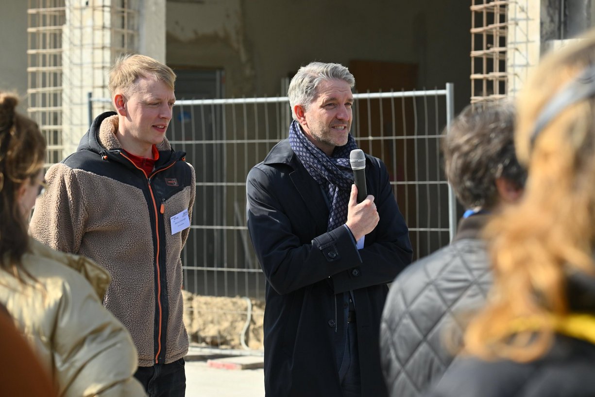 Laut Martin Sowinski, Mitglied der BIM-Geschäftsleitung, werden innovative Themen wie das serielle Sanieren im InnoLab der BIM aktiv vorangetrieben. Person mit Mikrofon in der Hand spricht zu einer Personengruppe.