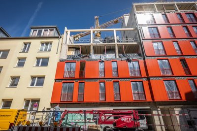Mehrstöckiges Gebäude während Sanierung mit roten vorgefertigten Fassadenelementen
