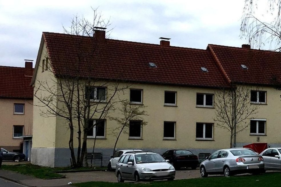 Unsaniertes Gebäude hinter Straße mit parkenden Autos