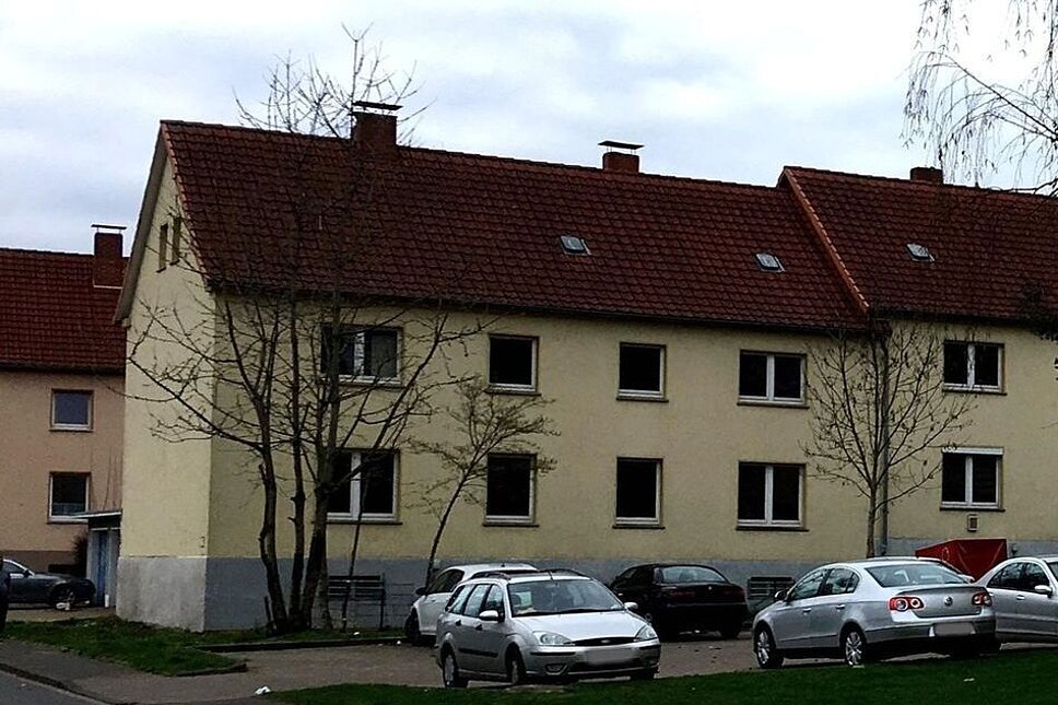 Unsaniertes Gebäude hinter Straße mit parkenden Autos