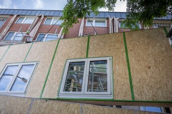 Vorgefertigtes Fassadenelement mit Fenstern, im Hintergrund ein Mehrfamilienhaus
