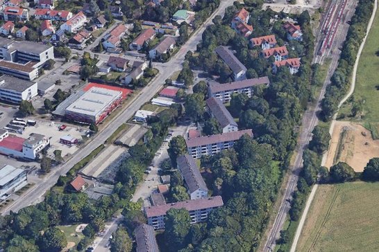 Luftaufnahme Wohnquartier, mehrere Gebäude, Straßen und Grünflächen mit großen Laubbäumen