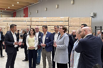 Personengruppe in Business-Kleidung in einem Werk, im Hintergrund Holzbalken