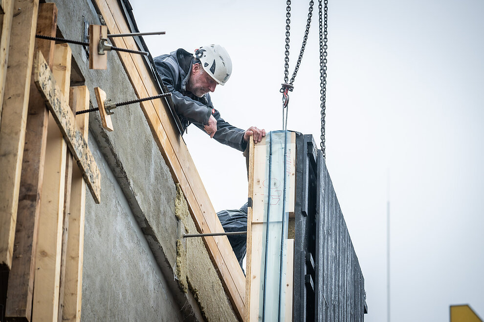 Fassadenelement wird von Bauarbeiter zum Gebäude navigiert.