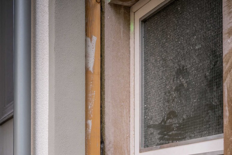 Baudetail: alte Fassade eines Gebäudes mit davor montiertem neuen Fassadenelement