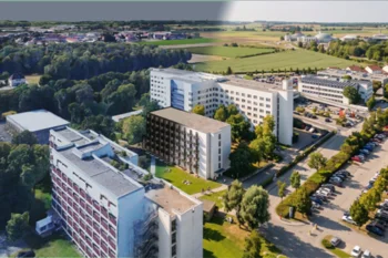 Blick von oben auf einen Komplex mit mehrgeschossigen Mehrfamilienhäusern, Grünanlagen, Bäumen und Anliegerstraßen.