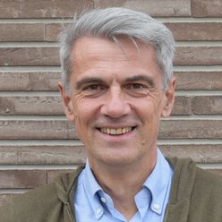 Porträt, Person mitkurzen Haaren, Hemd hellblau und Strickjacke