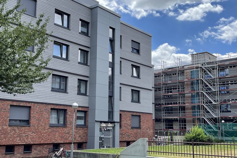 im Vordergrund: Wohngebäude saniert, im Hintergrund: Wohngebäude während Sanierung