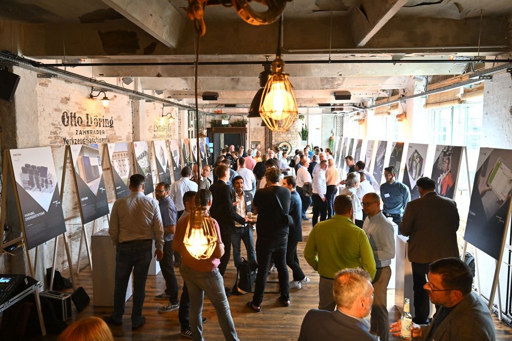 Innovationsmarkt mit ersten Gesprächen Halle mit vielen Leuten und Plakataufstellern an den Seiten, gemütlich beleuchtet