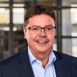 Person mit kurzen Haaren und Brille, Hemd und Sakko