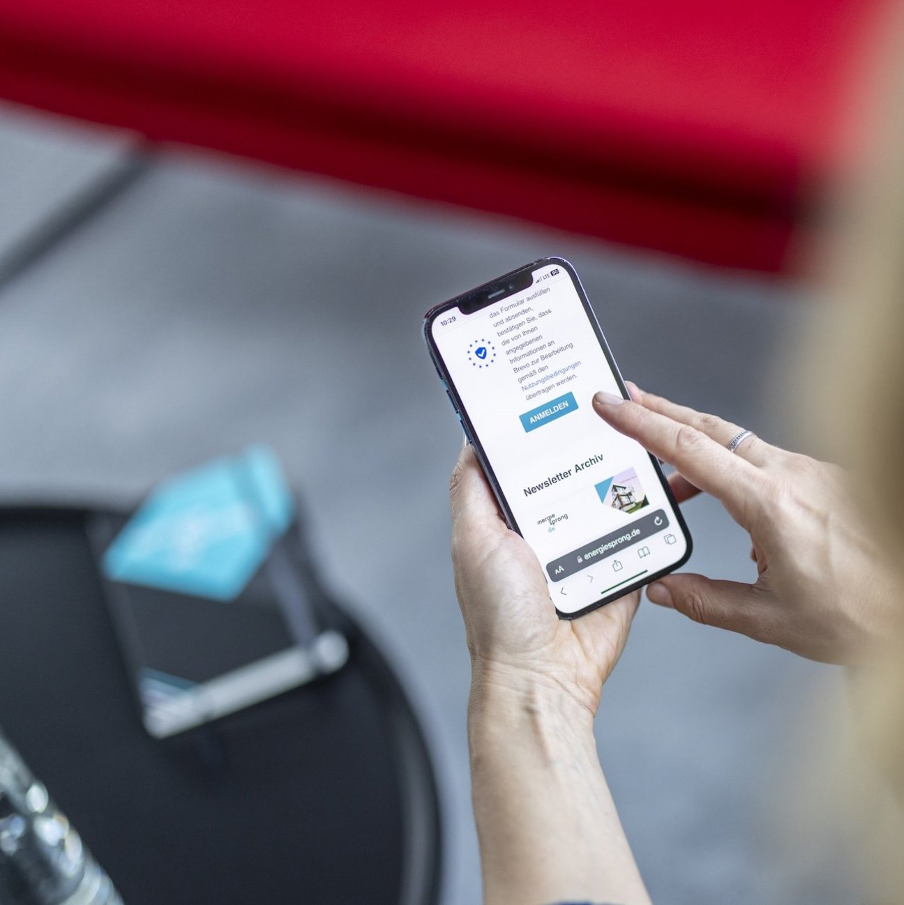 Zwei Hände halten ein Smartphone. Auf dem Display ist das Newsletter-Archiv der Website enegiesprong.de zu sehen.