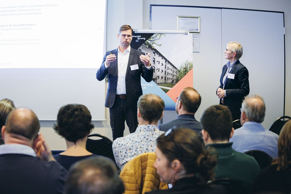 Dirk Förster-Wehle, Leiter Zentrale Technik bei der TAG Wohnen Person im Anzug referiert vor einer sitzenden Personengruppe.