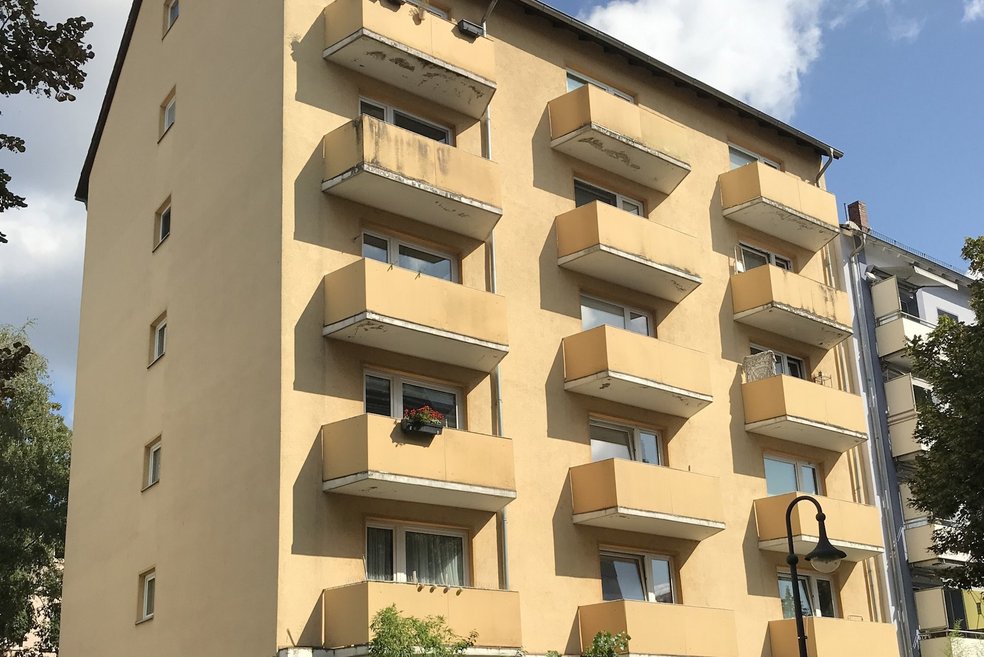 Mehrfamilienhaus fünfgeschossig mit Balkonen mit Putzfassade vor Sanierung