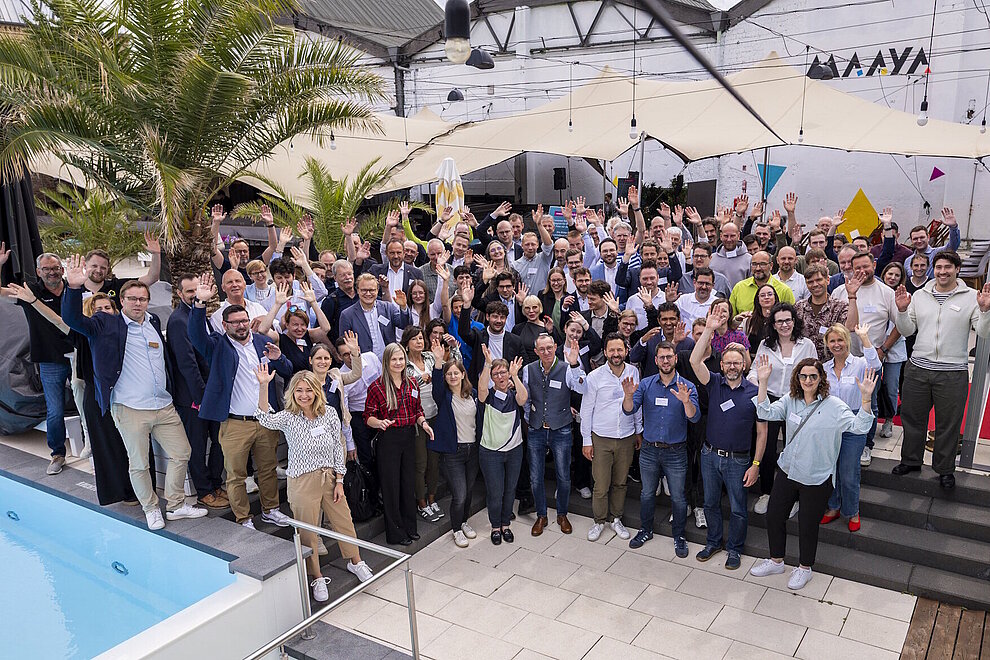 Gruppenbild mit circa 120 Personen an einem Pool