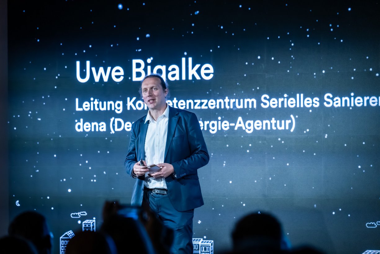 Person steht vor Publikum auf einer Bühne.