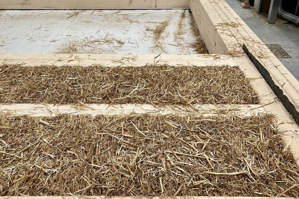 vorgefertigtes Fassadenelement mit Strohdämmung Bild zeigt Holzrahmen gefüllt mit Stroh in Fertigungshalle