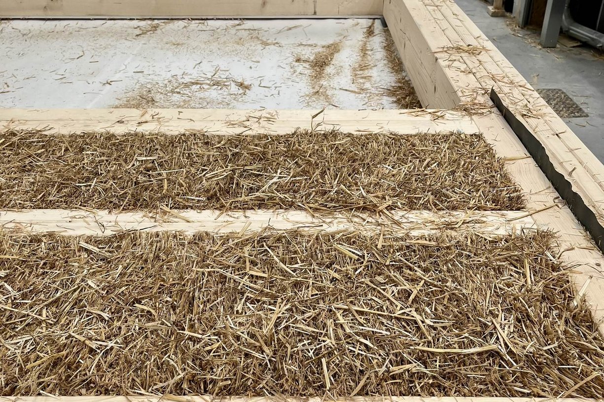vorgefertigtes Fassadenelement mit Strohdämmung Bild zeigt Holzrahmen gefüllt mit Stroh in Fertigungshalle
