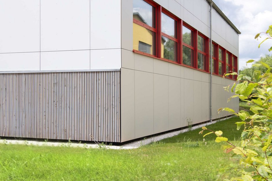Seitenansicht Turnhalle mit Fenster (Fassade in weiß, Fensterrahmen in rot)