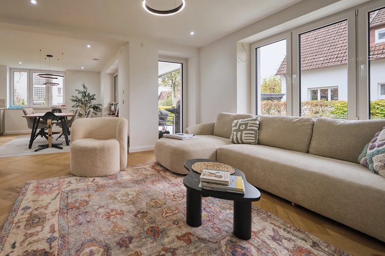Wohnzimmer mit Sofa, Teppich, großer Fensterfront
