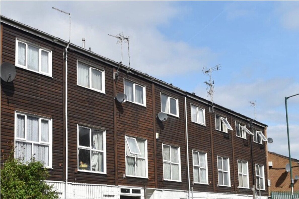 Wohnhaus unsaniert mit Fassade aus dunkelbraunem Holz