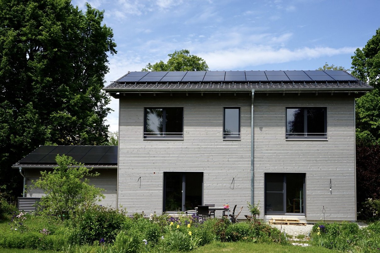 Das Haus der Familie Vordermayr nach Sanierung und Aufstockung. Bild zeigt saniertes Haus mit Vorgarten und Photovoltaikanlage auf dem Dach
