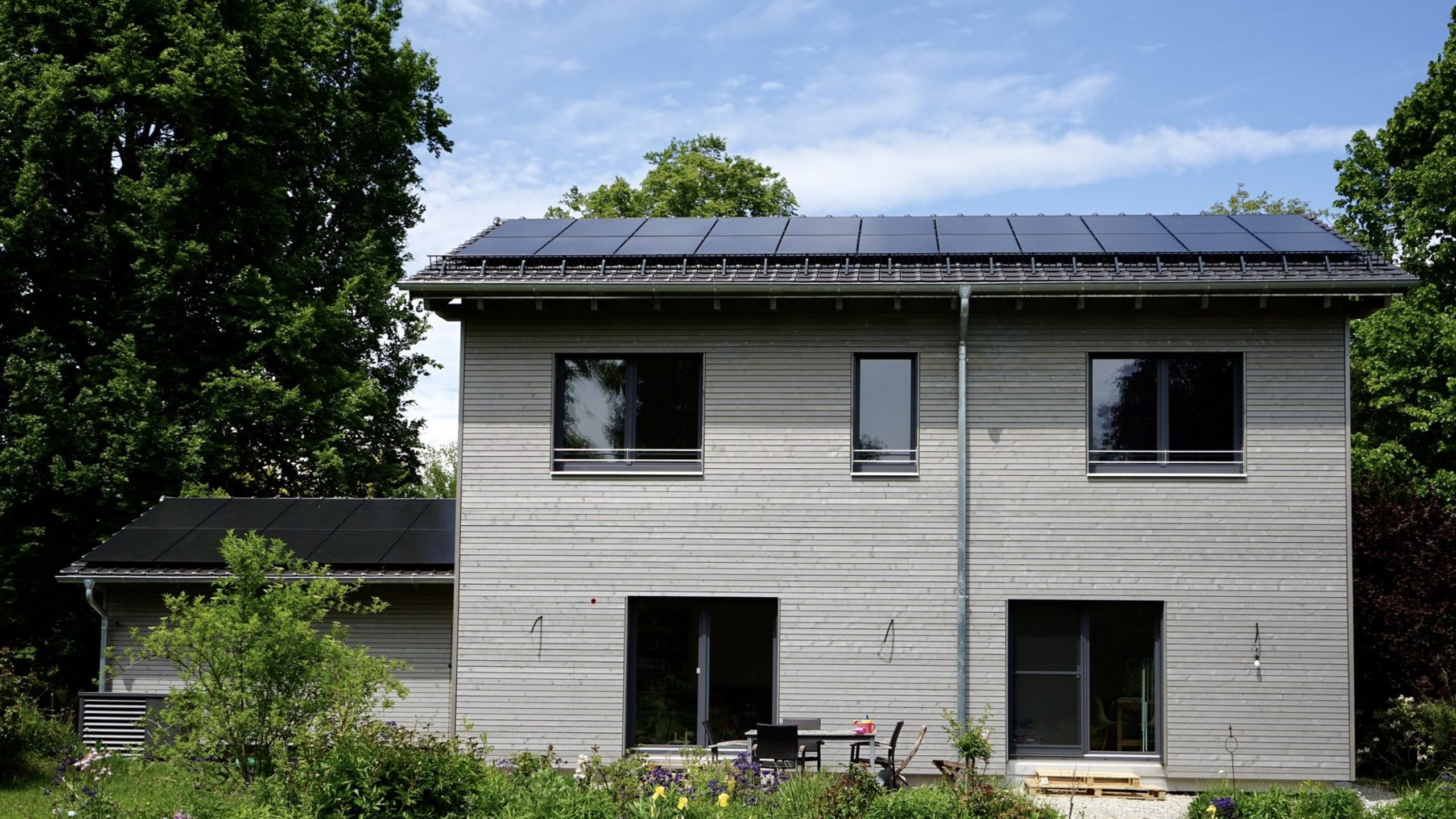 Bild zeigt saniertes Haus mit Vorgarten und Photovoltaikanlage auf dem Dach