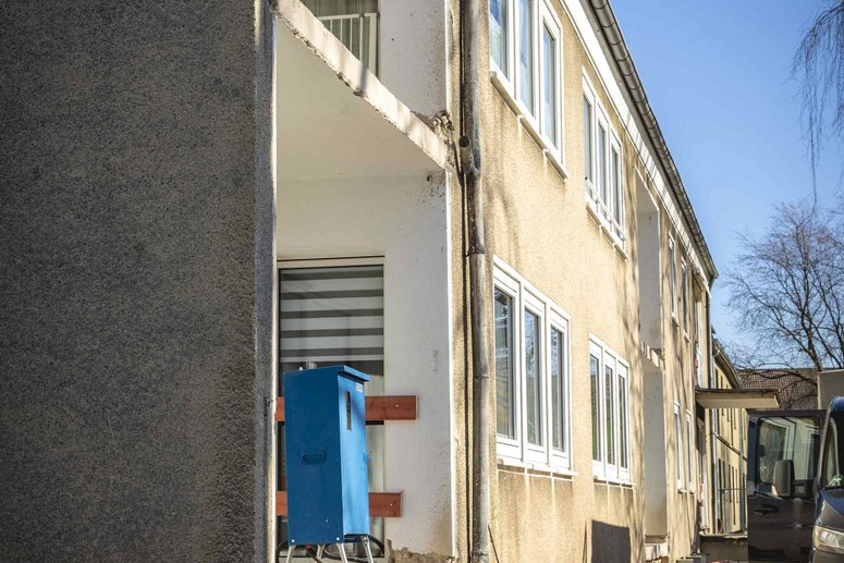 Blick entlang eines Mehrfamilienhaus zweigeschossig, Balkone ohne Geländer als Vorbereitung für Sanierung
