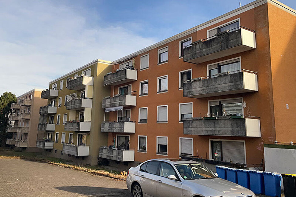 Mehrfamilienhaus viergeschossig, unsaniert, mit Balkonen. Davor steht ein PKW. 