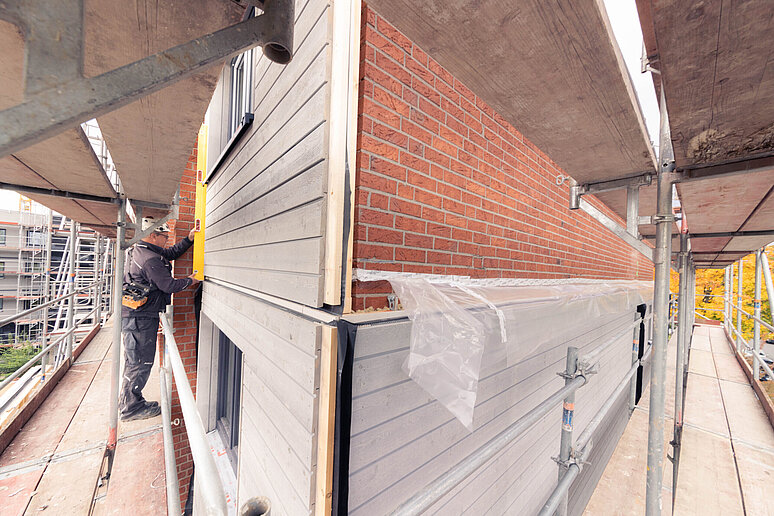 Hausfassade während Sanierung mit vorgefertigten Fassadenelementen