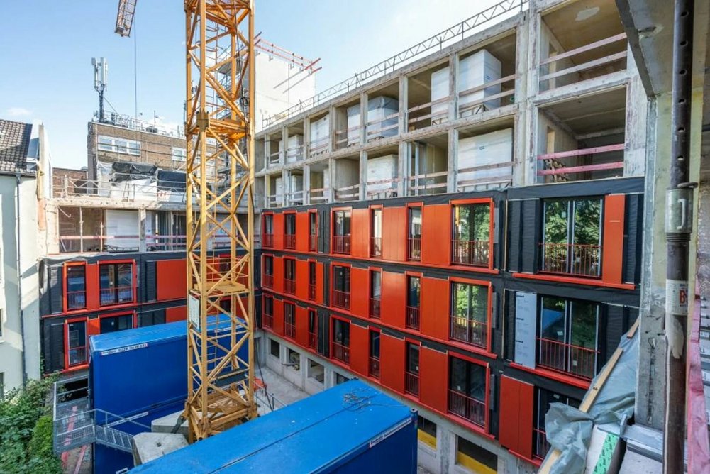 Wohngebäude während Sanierung mit vorgefertigten Fassadenelementen, Baustelle mit Kran