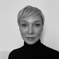 Portraitfoto in Schwarz-Weiß, Person mit kurzen hellen Haaren und im Rollkragenpullover