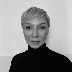 Portraitfoto in Schwarz-Weiß, Person mit kurzen hellen Haaren und im Rollkragenpullover