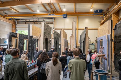 Personen schauen Vorfertigung von Hausfassadenelementen im Werk an.