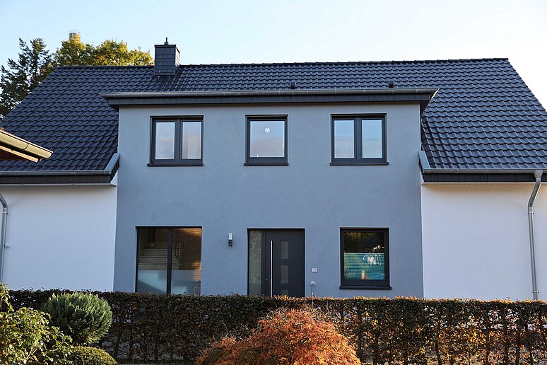 Hauseingang mit Fassade hinter Hecke