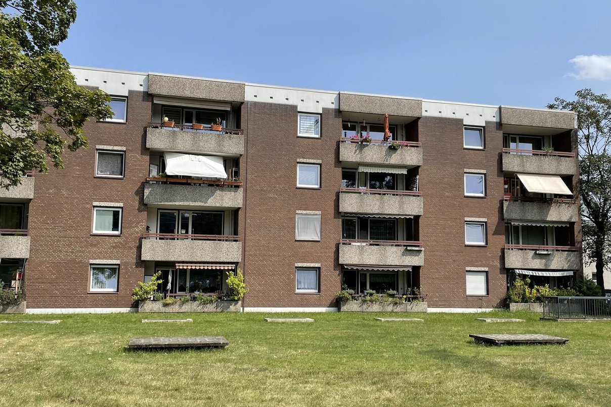 Mehrfamilienhaus viergeschossig mit Flachdach, Fenster und Balkone, davor Rasenfläche