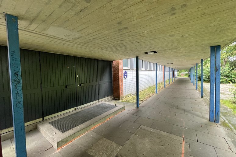 Weg mit Überdachung entlang eines Schulgebäudes
