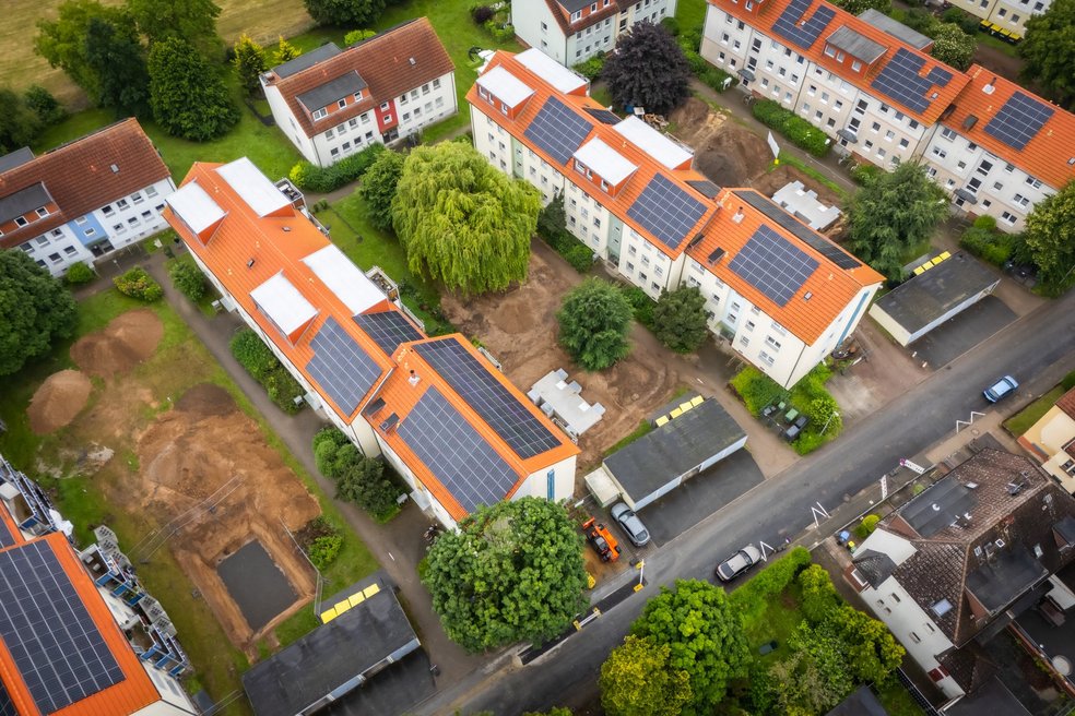 Blick von oben auf ein Wohngebiet mit Mehrfamilienhäusern, Dächer mit Photovoltaikanlagen