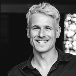 Porträt in schwarz und weiß, Person mit hellen, kurzen Haaren, schwarzes Hemd