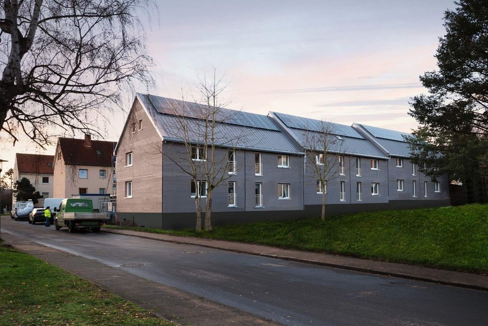 Das erste Energiesprong-Pilotprojekt in Hameln wurde von ecoworks mit vorgefertigten Dach- und Fassadenelementen sowie nachhaltiger Heiztechnik und Stromerzeugung auf NetZero-Standard gebracht. Gebäude vor Straße frisch saniert mit PV