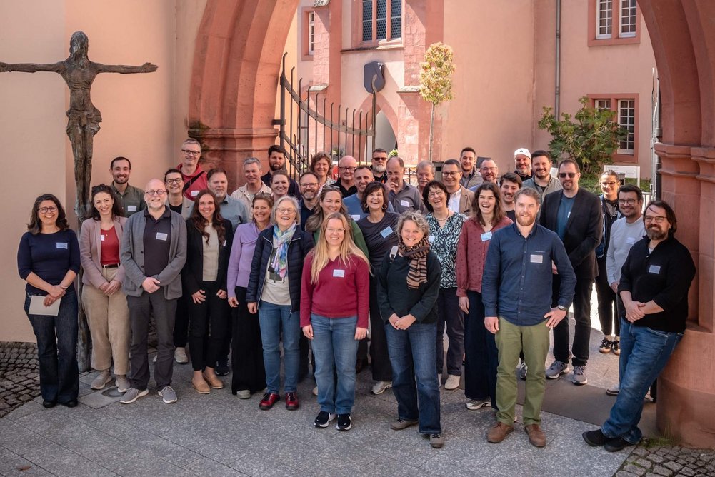 Personengruppe steht unter einem Torbogen für ein Gruppenfoto.