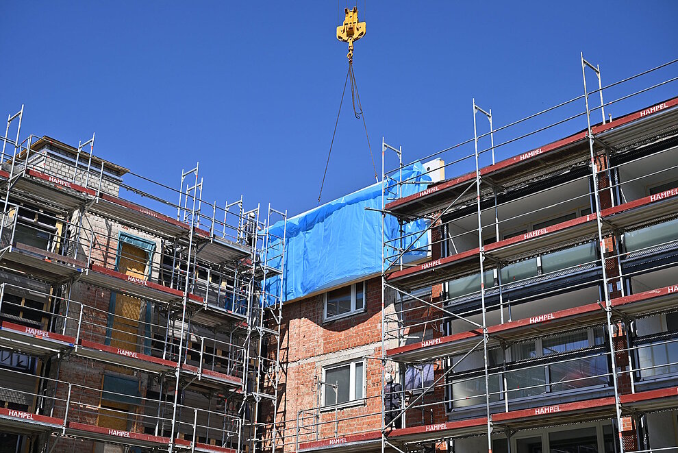 Fassadenelement wird mit Hilfe eines Krans zur Montage an der Hausfassade platziert.