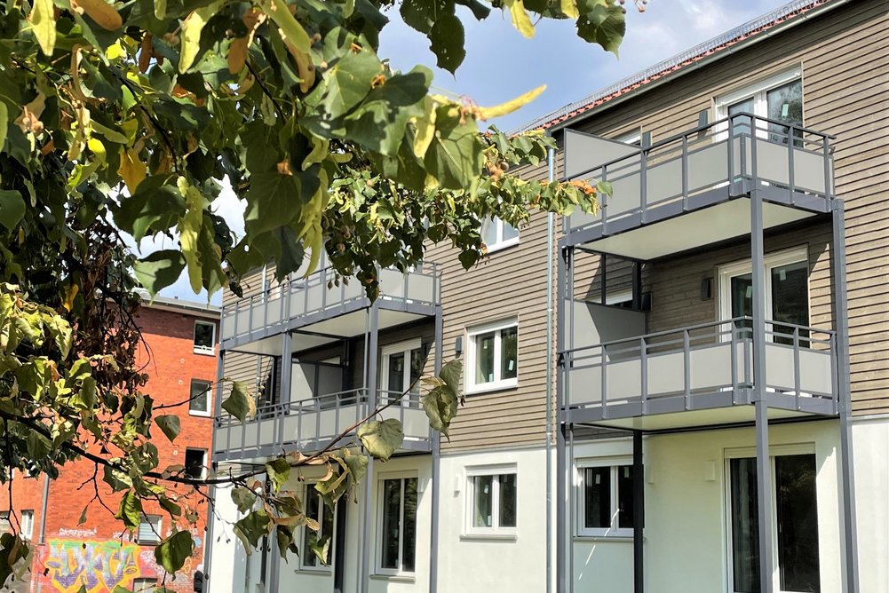 Mehrfamilienhaus dreigeschossig mit Balkonen während Sanierung, davor Grünfläche