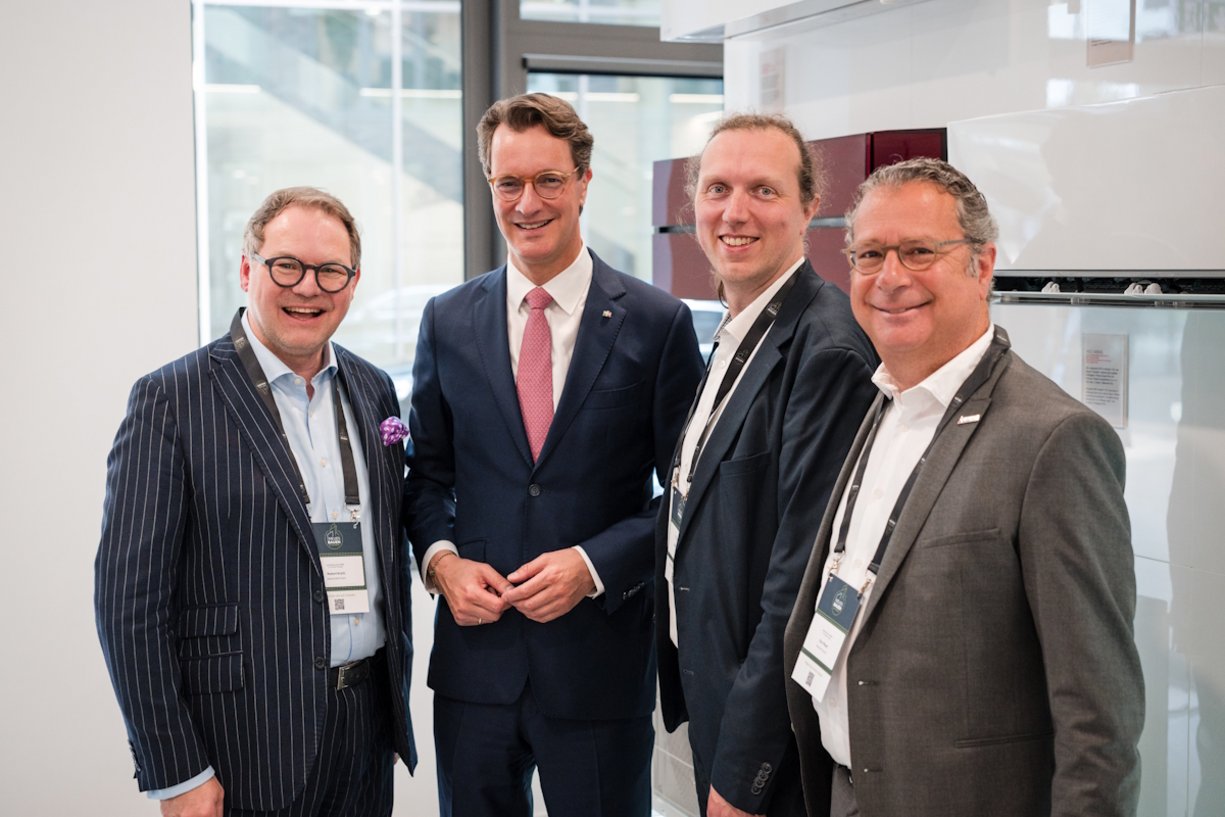 v.l.n.r.: Robert Kroth, Geschäftsführer Neues Bauen – 80 Sekunden; Hendrik Wüst, MdL,
Ministerpräsident des Landes Nordrhein-Westfalen; Uwe Bigalke, dena; Dror Peled, Mitsubishi Electric Vier Personen in Anzügen stehen nebeneinander für ein Gruppenbild.