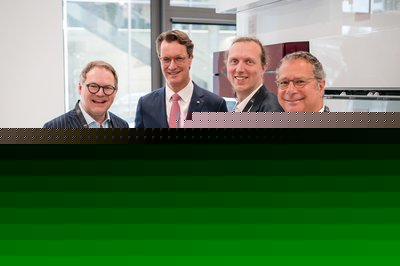 Vier Personen in Anzügen stehen nebeneinander für ein Gruppenbild.