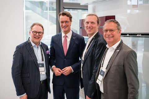 Vier Personen in Anzügen stehen nebeneinander für ein Gruppenbild.