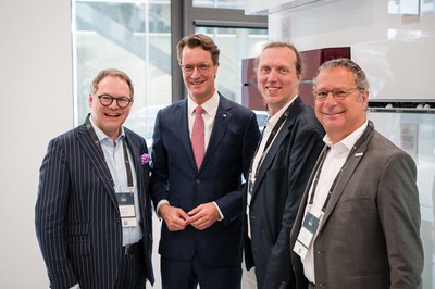 Vier Personen in Anzügen stehen nebeneinander für ein Gruppenbild.